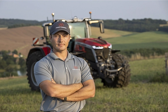 Massey Ferguson sales representative standing in front of a tractor in a rural field.